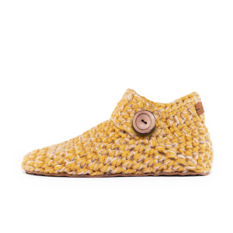 Side angle of a yellow wool slipper with wooden button fastening and suede leather sole. Handmade by Kingdom of Wow. Barefoot design for Men and Women.