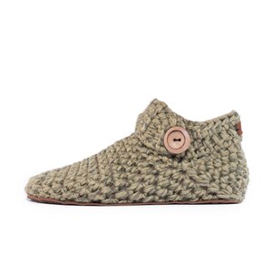 Side angle of a winter moss green wool slipper with wooden button fastening and suede leather sole. Hand-knitted by Kingdom of Wow. Barefoot design for Men and Women.