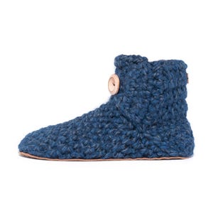 A navy blue hand knitted slipper boot with a wooden button closure. The slipper has a thick, textured knit and a leather sole. Barefoot slippers for indoor use. Warm, cozy and comfortable.