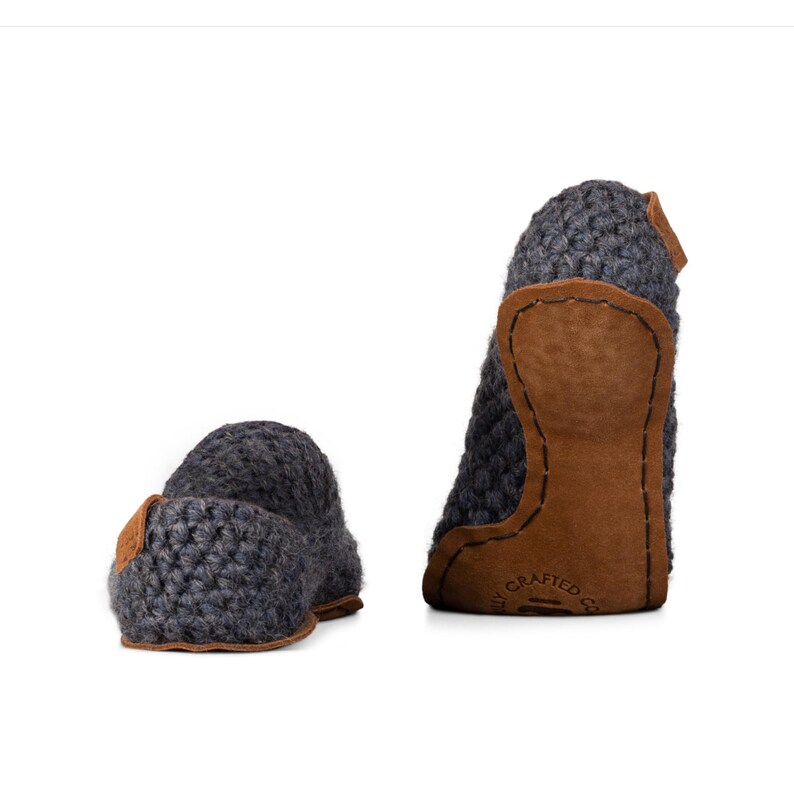 Peut inclure: Deux pantoufles en tricot gris avec des d&eacute;tails en cuir marron. Les pantoufles ont une texture en tricot &eacute;pais et un talon et une semelle en cuir. Con&ccedil;ues pour un usage int&eacute;rieur, elles sont pr&eacute;sent&eacute;es sur fond blanc.