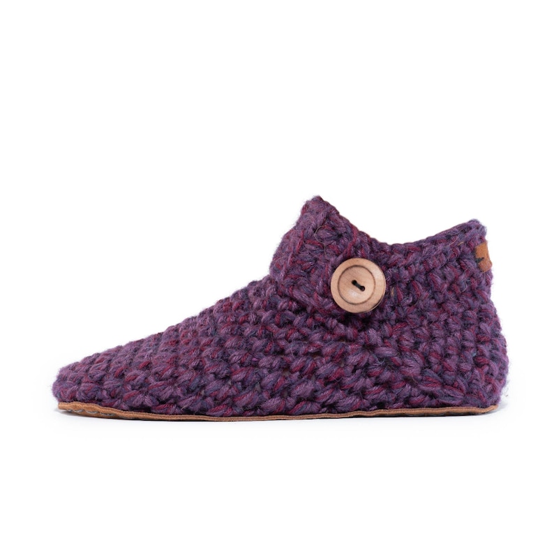 Side angle of a lavender purple wool slipper with wooden button fastening and suede leather sole. Hand-crocheted by Kingdom of Wow. Barefoot design for Men and Women.