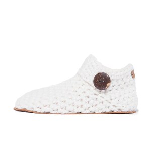 Side angle of a white wool slipper with wooden button fastening and suede leather sole. Handmade by Kingdom of Wow. Barefoot design for Men and Women.