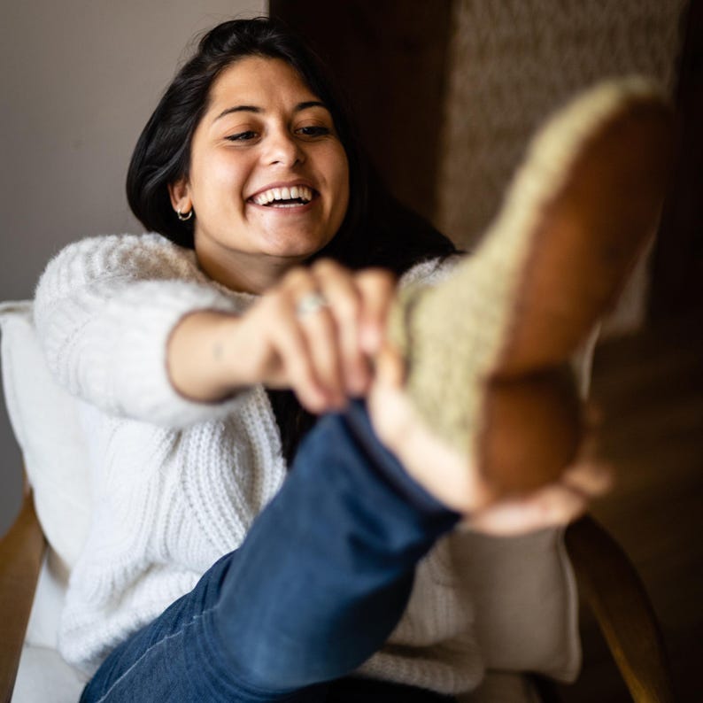 Smiling woman puts on green woolen slippers