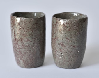 Handgemaakte raku-theekopjes, warmgrijs keramiek met bordeauxrode accenten