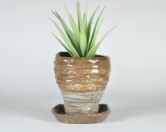 Maceta hecha de rollos de arcilla, en tonos marrón claro cálido y gris claro, cerámica Raku, para plantas pequeñas.