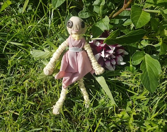 Inquietante y adorable muñeca momia con un vestido rosa