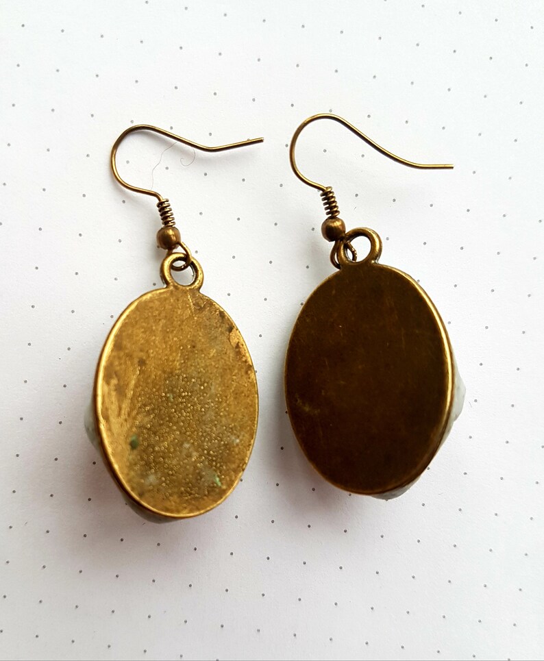 May include: A pair of oval-shaped earrings with a gold finish. The earrings have a simple design and are perfect for everyday wear.