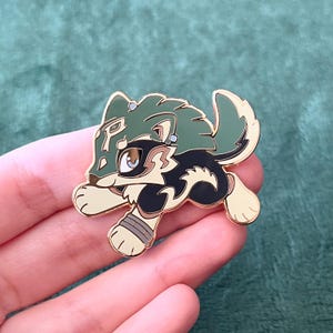 May include: A green and black enamel pin of a cartoon wolf wearing a green mask. The wolf is running and has a gold finish.