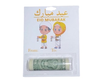 Könnte beinhalten: Eine weiße rechteckige Karte mit dem goldenen Schriftzug Eid Mubarak und Illustrationen von zwei Kindern mit Laternen. Unter dem Text befinden sich die Beschriftungen From und To sowie eine Blisterverpackung mit einem gerollten Ein-Dollar-Schein.