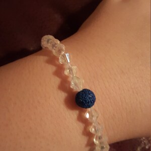 May include: A bracelet made of clear crystal beads with a single dark blue lava bead.