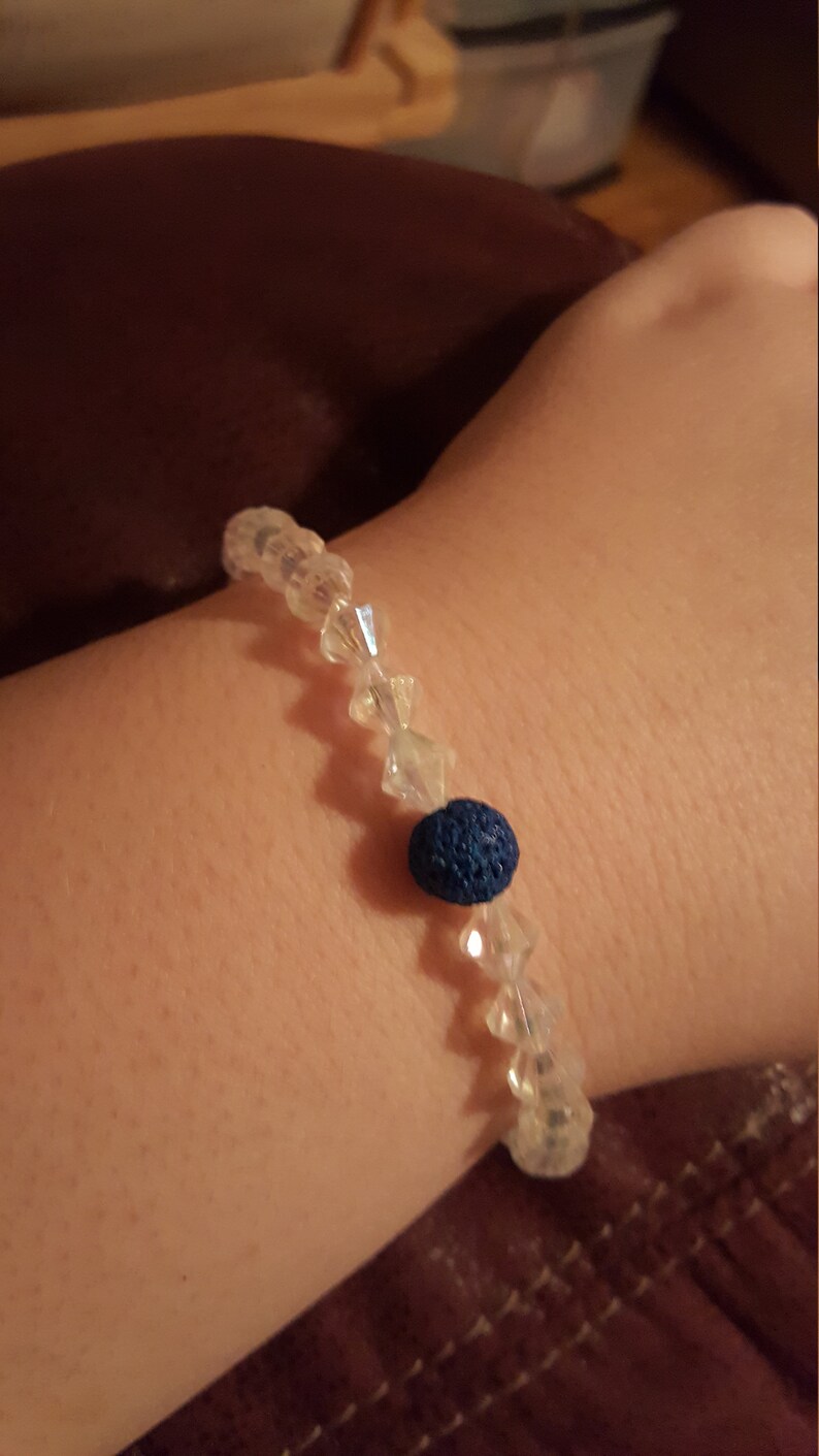 May include: A bracelet made of clear crystal beads with a single dark blue lava bead.