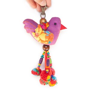 May include: Purple fabric bird keychain with a colorful floral pattern and red, orange, yellow, green, blue, and purple tassels.