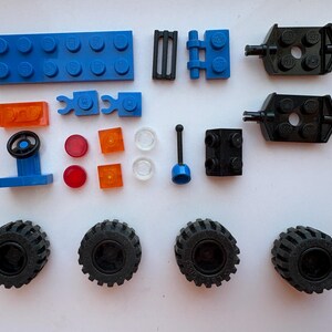 May include: Assorted colorful toy building blocks, including a blue base, black wheels, and various other pieces. The set includes a steering wheel, orange and red translucent pieces, and black connectors.