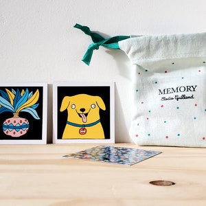 Peut inclure: Ensemble de cartes illustrées avec un chien et une plante sur fond noir. Un sac vert clair à pois rouges et verts avec le mot "MEMORY" est également présent. Le sac est noué avec un ruban vert.