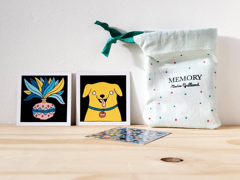Peut inclure: Ensemble de cartes illustr&eacute;es avec un chien et une plante sur fond noir. Un sac vert clair &agrave; pois rouges et verts avec le mot "MEMORY" est &eacute;galement pr&eacute;sent. Le sac est nou&eacute; avec un ruban vert.
