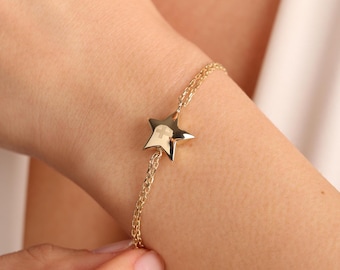 May include: A gold chain bracelet with a star charm. The star has a small cross engraved on it.