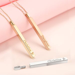 May include: Two rose gold-toned vertical bar pendant necklaces, one engraved with "Christine" and a heart, the other with "Daughter". A separate silver-toned bar pendant is shown with a screw-in top piece, engraved with "Christine" and a heart.