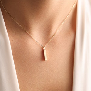 May include: A gold-toned necklace featuring a slender, rectangular bar pendant suspended from a delicate chain. The vertical bar pendant is engraved with the text "Always in my heart" and a small heart symbol, creating a simple and refined piece of jewellery.
