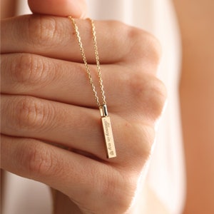 May include: A gold-toned vertical bar pendant necklace featuring a delicate chain. The rectangular bar is engraved with the text "Always in my" followed by a small heart symbol. The piece has a polished metallic finish and a simple link chain.