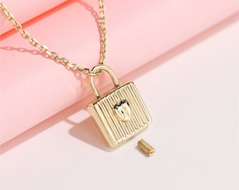 May include: A gold necklace with a padlock pendant featuring a heart design. The padlock is open and a small screw is visible next to it.