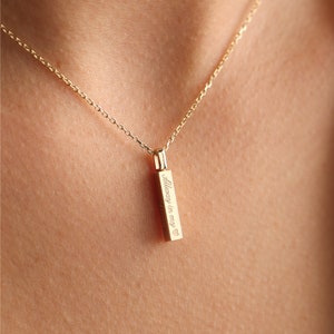 May include: A gold-toned vertical bar pendant necklace featuring a delicate chain and an engraved inscription that reads Always in my heart with a small heart symbol at the end of the text, suspended from a thin, polished gold-coloured metal chain.