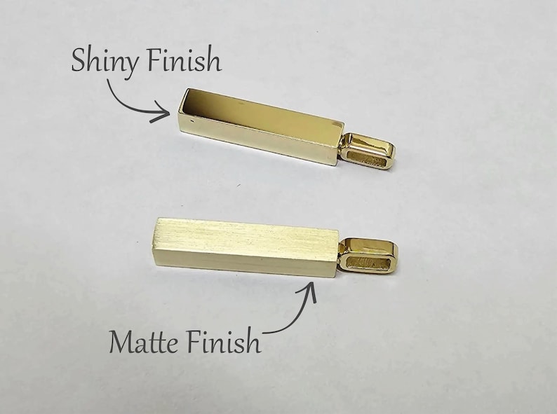 May include: Two gold-coloured rectangular bar pendants with attached bails. The top pendant features a shiny finish, while the bottom pendant has a matte finish. Text labels indicate Shiny Finish and Matte Finish for each respective pendant.