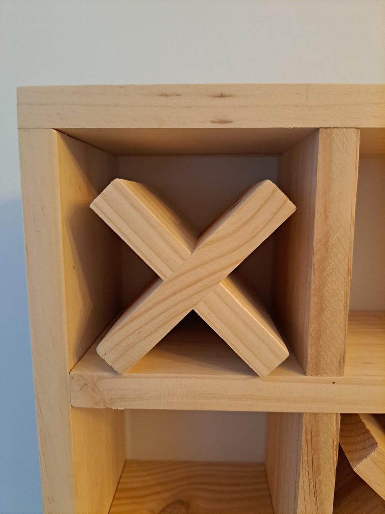 Puede incluir: Un estante de vino de madera con un dise&ntilde;o en forma de cruz para guardar botellas de vino. El estante est&aacute; hecho de madera natural y tiene un color marr&oacute;n claro.