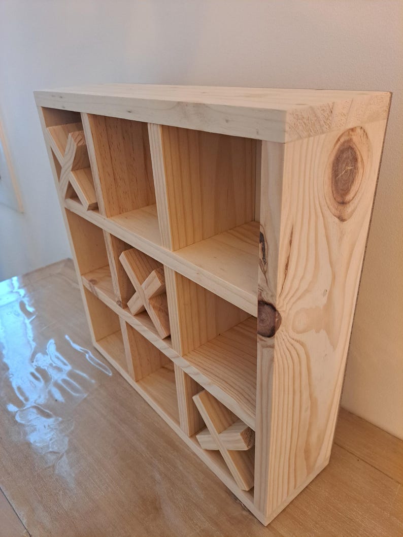 Puede incluir: Una estanter&iacute;a de madera con un dise&ntilde;o de tres en raya. La estanter&iacute;a est&aacute; hecha de madera natural y tiene nueve compartimentos.