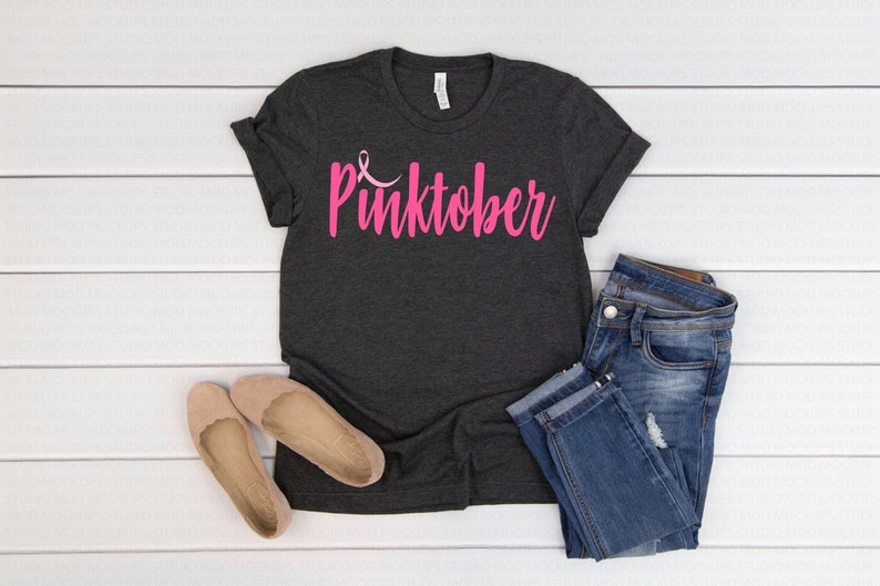 May include: A dark grey t-shirt with the words "Pinktober" in pink lettering and a pink ribbon symbol.