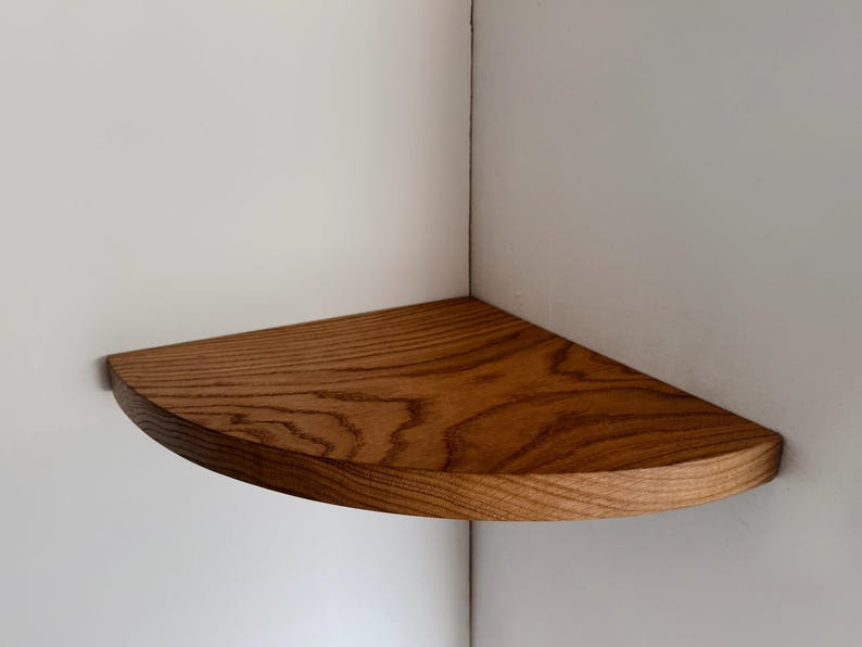 May include: A wooden corner shelf with a rounded edge and a natural wood finish.