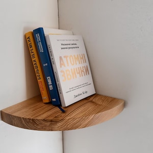 May include: A wooden corner shelf with three books on it. The books are titled "Большая Перемена", "История Идеи", and "Atomic Habits".