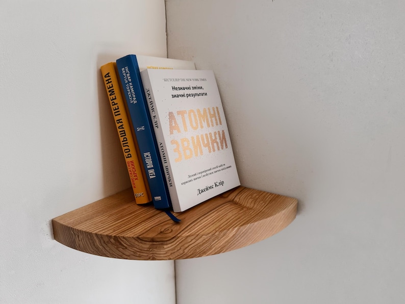 May include: A wooden corner shelf with three books on it. The books are titled "Большая Перемена", "История Идеи", and "Atomic Habits".