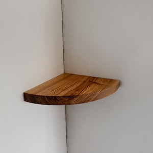 May include: A wooden corner shelf with a rounded edge and a natural wood grain finish.