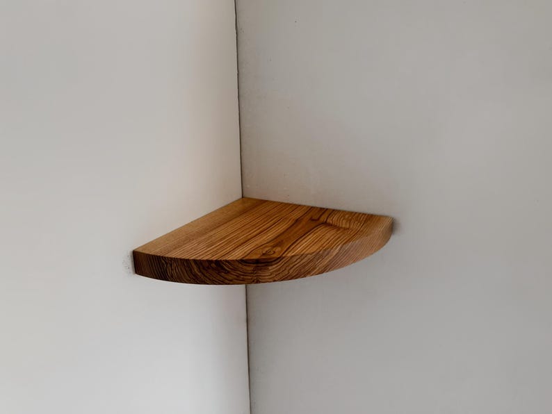 May include: A wooden corner shelf with a rounded edge and a natural wood grain finish.