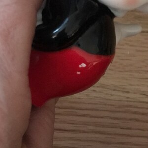 Pu&ograve; includere: Una statuetta in ceramica di Topolino, con i suoi pantaloncini rossi e le scarpe nere iconiche. La statuetta &egrave; dipinta in nero, bianco e rosso.