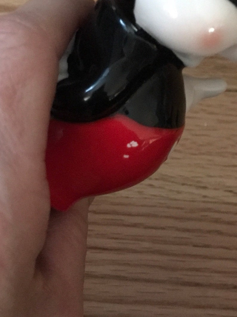 Pu&ograve; includere: Una statuetta in ceramica di Topolino, con i suoi pantaloncini rossi e le scarpe nere iconiche. La statuetta &egrave; dipinta in nero, bianco e rosso.
