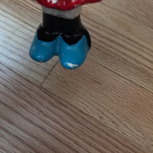Pu&ograve; includere: Una statuetta in ceramica di un personaggio dei cartoni animati che indossa un vestito rosso con pois bianchi e scarpe blu.