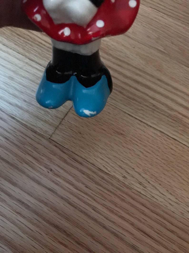 Pu&ograve; includere: Una statuetta in ceramica di un personaggio dei cartoni animati che indossa un vestito rosso con pois bianchi e scarpe blu.