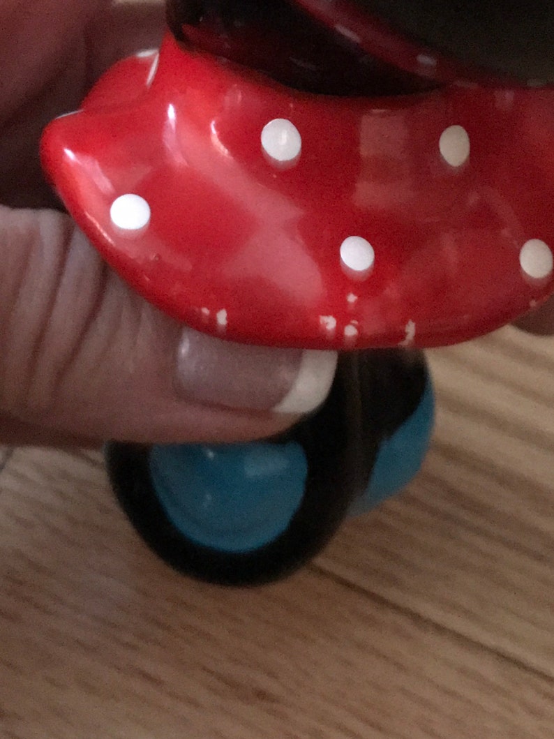 Pu&ograve; includere: Una statuetta in ceramica di una donna con i capelli neri e una gonna blu, decorata con pois rossi e bianchi. La statuetta &egrave; su ruote.