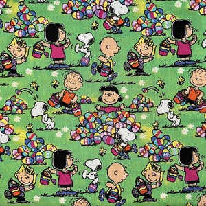 May include: A green fabric with a repeating pattern of cartoon characters holding baskets of colorful Easter eggs. The characters include Charlie Brown, Snoopy, and Lucy.