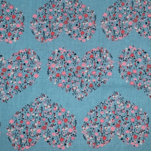May include: A blue fabric with a repeating pattern of pink and white floral hearts. The fabric has a subtle texture.