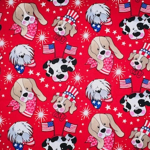 May include: A repeating pattern of cartoon dog faces on a red background. The dogs are wearing patriotic accessories like bandanas, hats, and headbands with American flags. White starbursts and stars fill the spaces between the dogs.