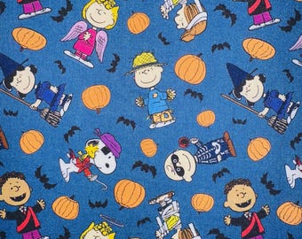 May include: A blue fabric featuring a repeating pattern of Halloween-themed cartoon characters, orange pumpkins, and black bats. The characters are dressed in costumes, including a vampire, angel, witch, and mummy.