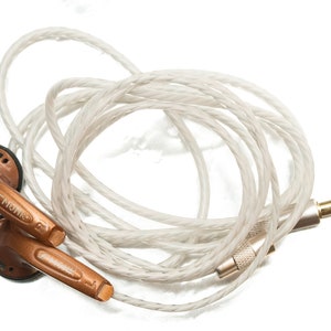 K&ouml;nnte beinhalten: Ein Paar kupferfarbene In-Ear-Kopfh&ouml;rer mit einem wei&szlig;en geflochtenen Kabel und einem vergoldeten 3,5-mm-Stecker.