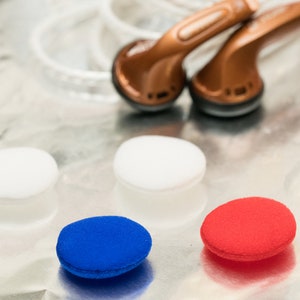 K&ouml;nnte beinhalten: Drei Paar Ohrst&ouml;psel in Wei&szlig;, Blau und Rot. Die St&ouml;psel sind aus Schaumstoff und so konzipiert, dass sie bequem im Ohr sitzen.