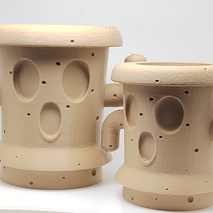 May include: Two beige, cactus-shaped planters with oval cutouts and small holes. The planters have a cylindrical body, a flared base, and a flat top. The planters have curved arm-like protrusions on the sides.