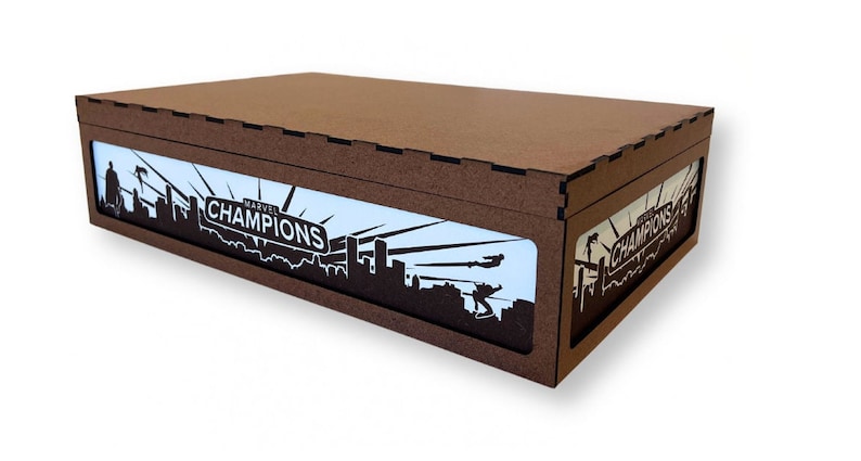 May include: A brown wooden box with a cutout design featuring a cityscape and the text "MARVEL CHAMPIONS".