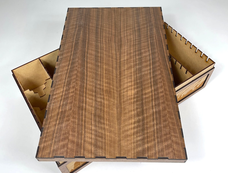 May include: A wooden box with a lid that opens to reveal compartments for organizing game pieces. The lid is made of a dark wood with a natural grain pattern.