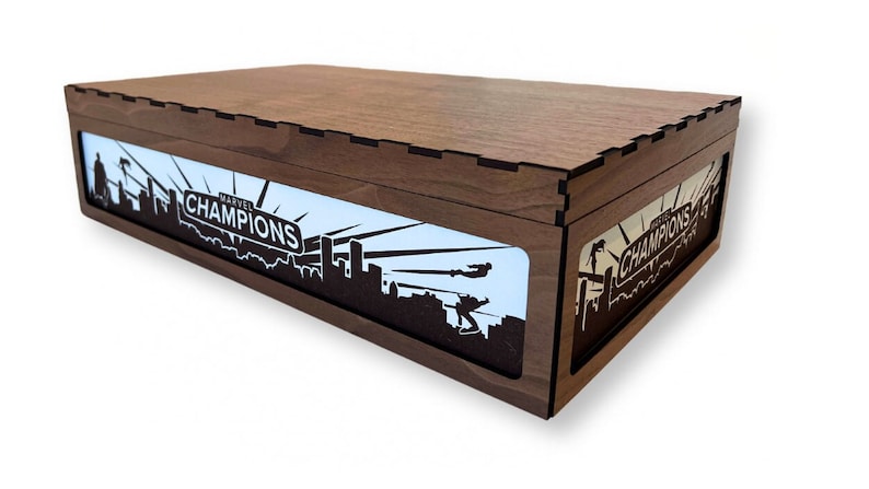 May include: A wooden box with a light blue interior and a black silhouette of a city skyline with the text "MARVEL CHAMPIONS" on a sign. The box is closed.