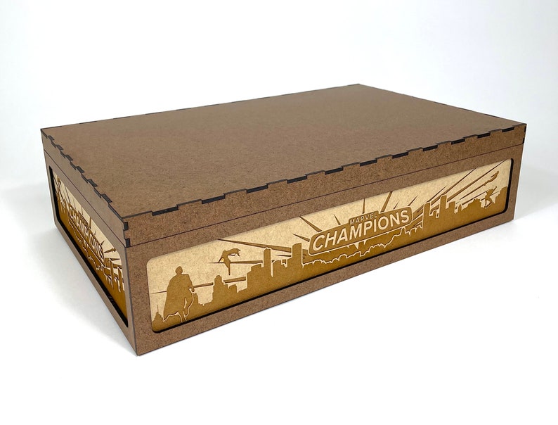 May include: A brown wooden box with a lid. The box has a Marvel Champions logo on the front with a cityscape and a superhero silhouette.